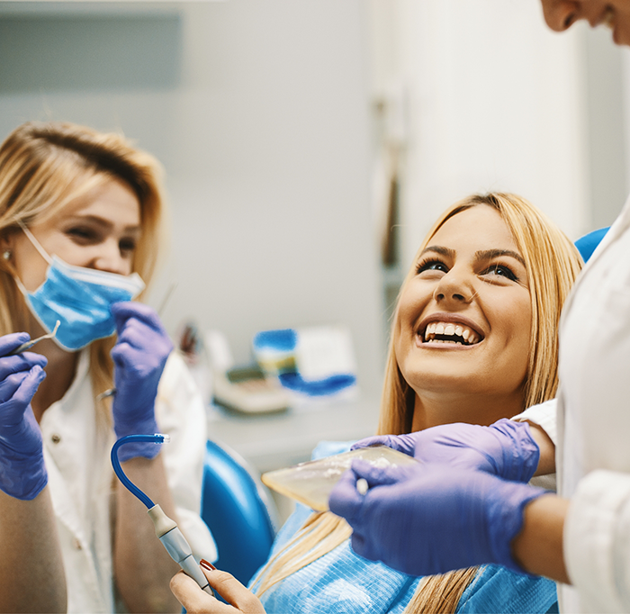 Dental patient smiling and looking up at two dentists