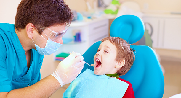 Male dentist examining a small childs teeth