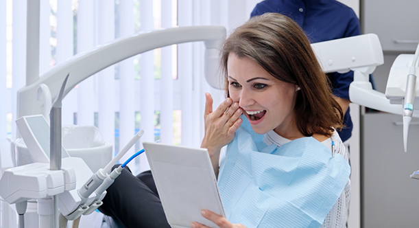 Woman in dental chair checking teeth in mirror