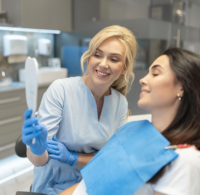 Female dentist holding mirror for dental patient