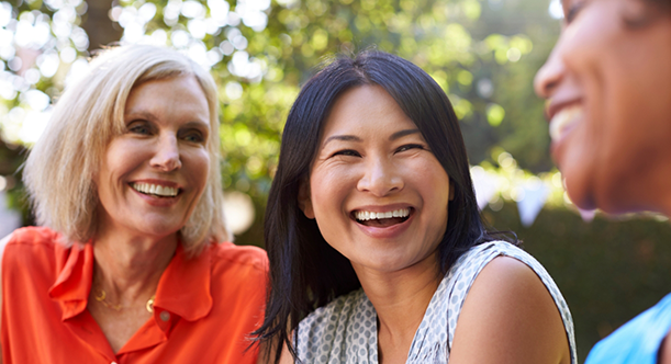 Three women sitting together outside and smiling