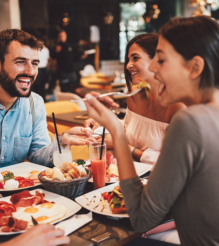 People smiling and eating a meal together at a table