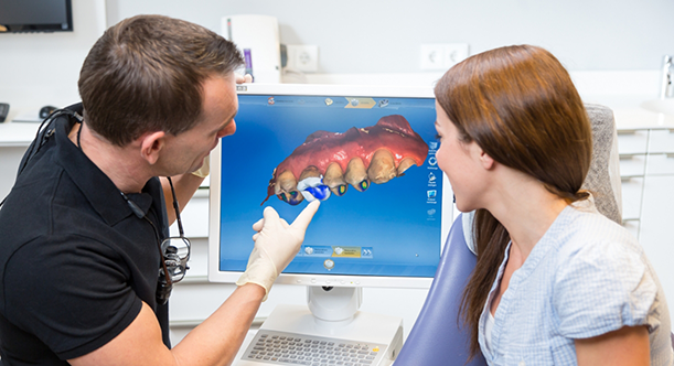 Dentist showing dental patient digital scan of teeth on monitor