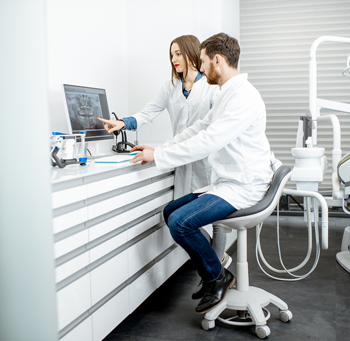 Two dentists looking at X ray of teeth