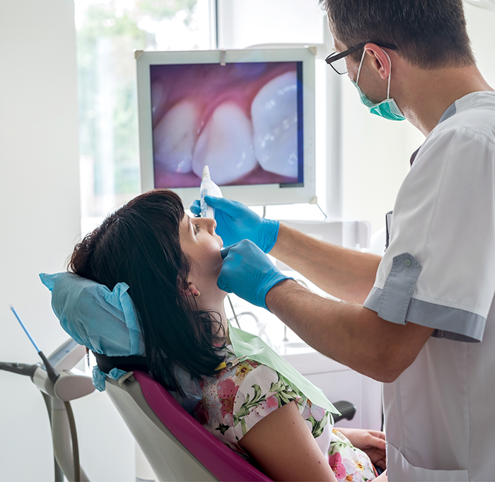 Dentist checking female patients teeth with intraoral camera