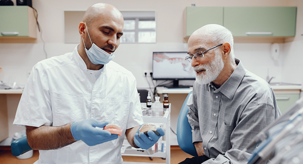 Dentist showing senior patient dentures in Idaho Falls