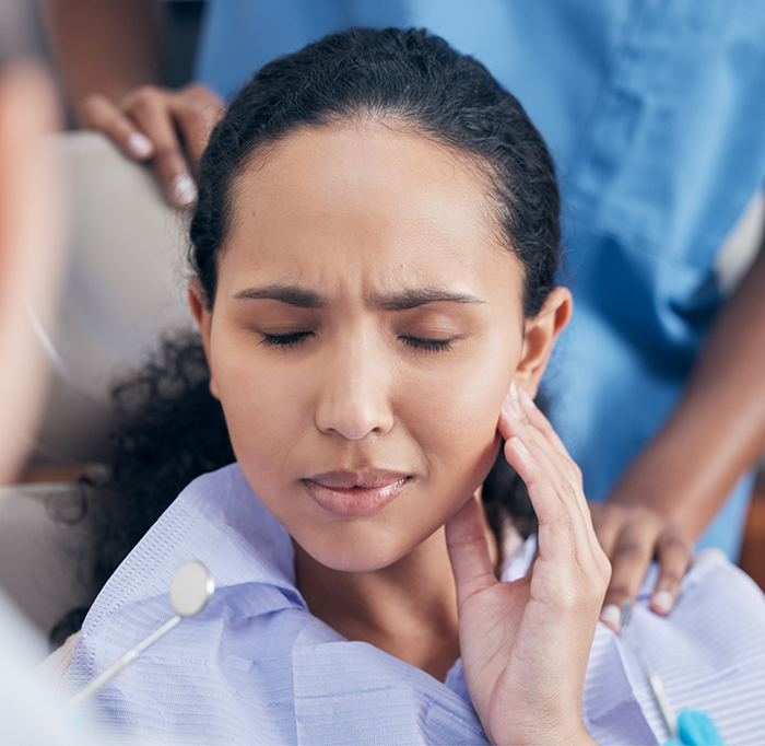 Close up of female dental patient rubbing jaw in pain