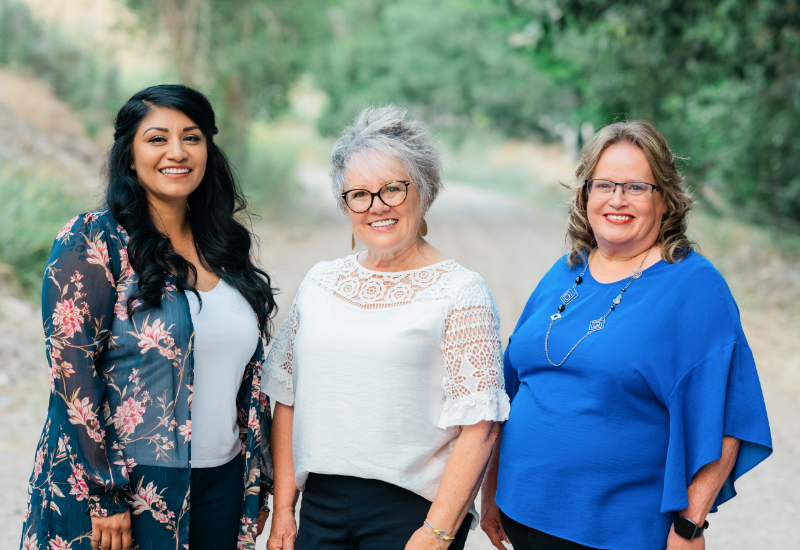 Three women standing together outside and smiling