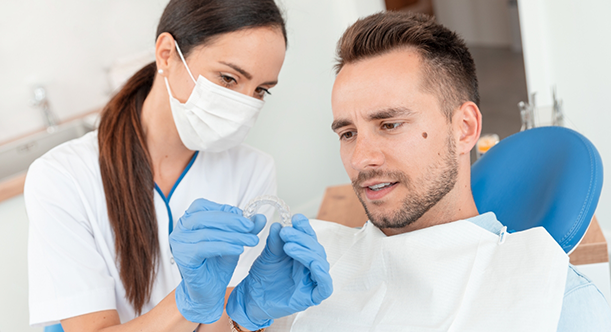 Female dentist showing male patient an Invisalign clear aligner in Idaho Falls