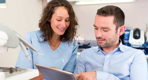 Female dentist showing male patient a tablet