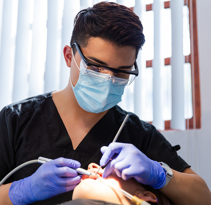 Dentist with mask performing a checkup and cleaning