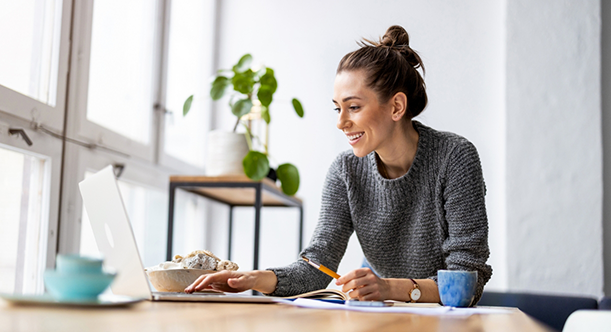 Woman typing on a laptop on a wooden table