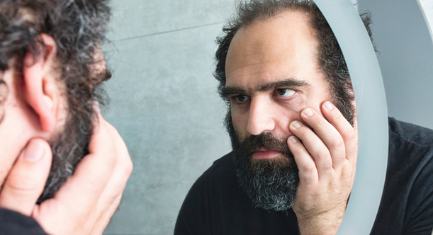 Man with tooth pain looking in a mirror