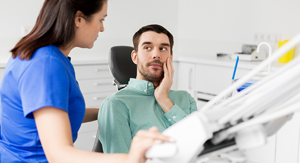 Man with toothache looking up at female dentist